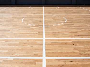 Straight-on architectural view of crisp painted court lines on a polished wooden floor, high-contrast industrial tones, clean lines.