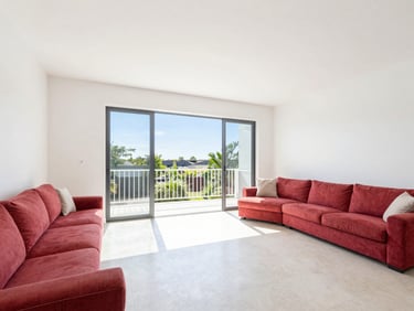 Spacious family living room with wide balcony, bright natural light, clean white walls, warm atmosphere.