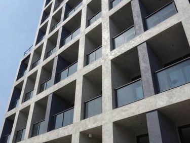 Sharp architectural exterior shot of a modern residential building in Dhaka, concrete gray and deep navy tones, crisp daylight, high-contrast shadows