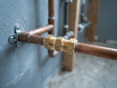 A clean copper pipe repair joint with a shiny brass coupling on a domestic water line, bright lighting