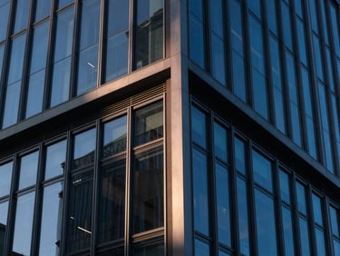 Close-up of a modern corporate building facade with glass and steel, sharp angles, blue hour, high contrast