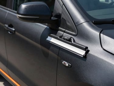 Close-up of a premium matte black corporate vehicle wrap being applied with precision squeegee tools, orange accent lines visible.
