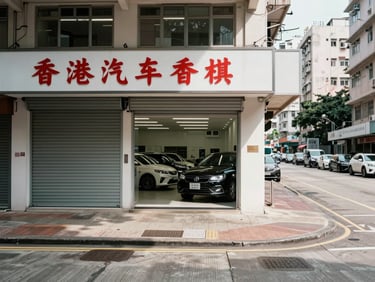 Wide panoramic street-level photograph of a Hong Kong car dealership shopfront in Cheung Sha Wan, taken from the pavement directly facing the entrance — roll-up metal gate half-open, a row of vehicles visible inside the showroom floor, Chinese signage above the door, overcast Hong Kong daylight, sharp shadows on the concrete, no people, full-width environmental framing with the signage in the left third and open road to the right