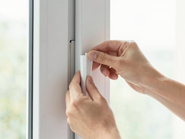 Detail shot of clean hands carefully applying high-quality insulation seal around a window frame, bright high-key lighting.