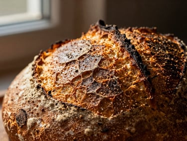 Extreme close-up of a dark-golden sourdough crust, blistered surface, dramatic window side-light, rich earthy tones, macro depth of field.