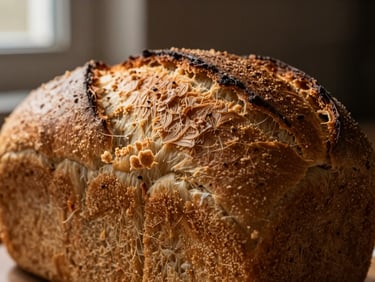 Macro shot of a freshly baked brioche loaf, golden-brown crust, soft texture visible, low-key directional side-lighting, warm earthy tones.