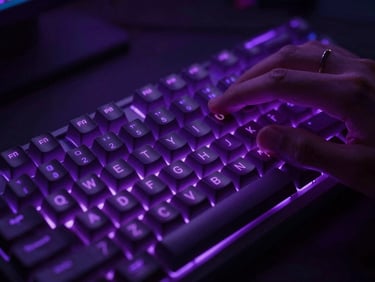 Close-up of hands on a mechanical keyboard with glowing RGB cyber purple backlighting, dark atmospheric editing bay.