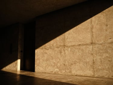 Low-angle architectural shot of a minimalist hotel lobby, deep shadows, warm amber light grazing a textured concrete wall, 35mm film grain