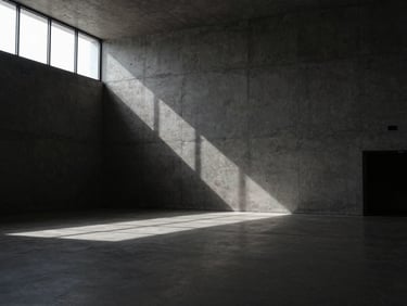 Interior wide-angle shot of a minimalist cultural center, massive raw concrete walls, dramatic natural light from high windows creating harsh shadows on the floor, desaturated charcoal tones.
