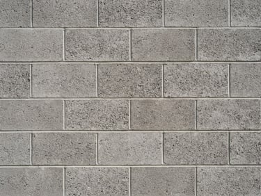 Close-up of perfectly aligned gray concrete blocks and clean mortar lines, bright afternoon sun highlighting the texture of the masonry