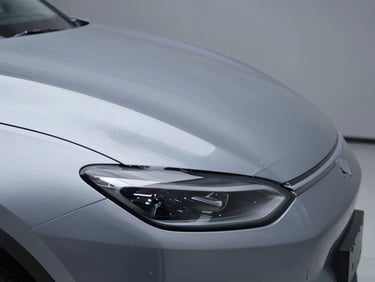 Extreme close-up of paint protection film applied to the leading edge of a vehicle hood, studio strobe lighting revealing the film's barely-there surface tension, cool neutral background, surgical framing emphasizing the precise film edge