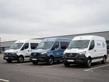 Three matching commercial vans in a clean urban parking bay, each wrapped in cohesive brand graphics, overcast daylight reading as neutral and controlled, low-angle 45-degree shot emphasizing the fleet's visual unity and three-dimensionality