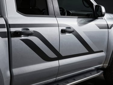 Overhead 45-degree shot of a pickup truck door panel with a precisely applied custom graphic, bold geometric lines in monochrome silver and black, studio strobe lighting sculpting the surface detail, minimal dark background