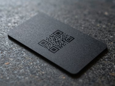 A matte-black smart business card with a clean laser-engraved QR code resting on a polished dark stone surface.