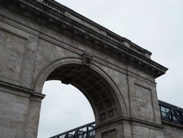 Low-angle shot of a classic stone archway meeting modern steel structure in London, overcast sky, architectural minimalism
