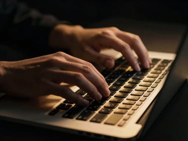 Close-up of hands typing on a glowing laptop keyboard in a dark room, golden reflections on the keys, high-contrast cinematic.