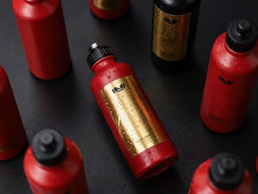 Overhead table layout showing custom-branded corporate water bottles with metallic gold foil labels, dark background.