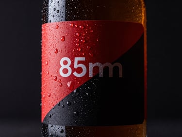 Macro close-up of a premium glass bottle with custom label, sharp condensation droplets, dramatic low-key studio lighting on a dark background, 85mm.