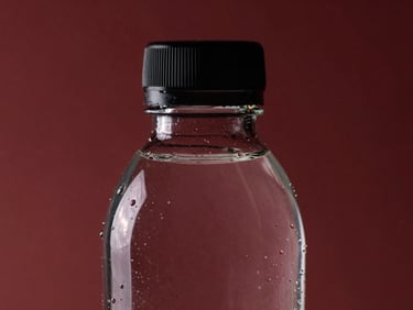 Macro close-up of a 330ml premium glass water bottle, clear glass, minimalist black cap, sharp studio reflections.