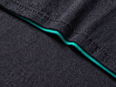 Extreme close-up of thick screen-printed ink texture on a dark slate heavyweight cotton t-shirt, glowing teal accent lighting highlighting the sharp vector edge