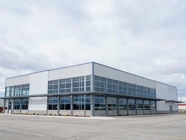 Wide-angle exterior shot of a modern steel-framed commercial building under construction in Idaho, bright cloudy day, 35mm lens.