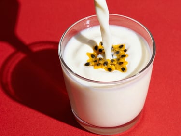 Thick creamy yogurt drink poured into a glass, real passion fruit seeds visible, high-contrast red background, sharp shadows, 50mm lens.