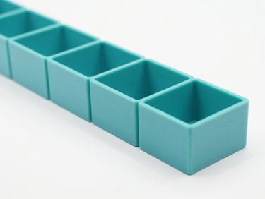 A neat row of custom turquoise 3D printed geometric organizers on a clean white surface, sharp focus, minimalist composition