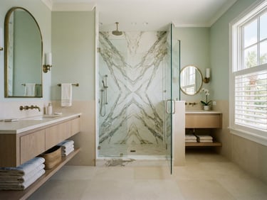Straight-on architectural elevation of a sun-drenched Boca Grande master bath featuring large-format book-matched marble walls, bright natural coastal daylight, pale sage and sand tones, 35mm