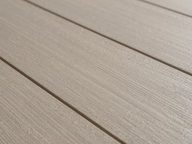 Macro shot of luxury vinyl plank surface texture, stone-effect pattern in warm greige, embossed grain detail catching raking side light, no people