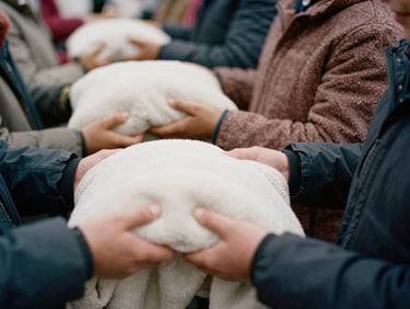 Hands distributing warm blankets to people queuing, soft light, candid, documentary style.