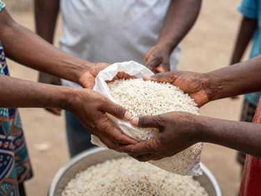 A volunteer handing a bag of rice to a community member, focus on hands, candid, documentary style.