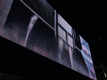 Sleek urban digital screens in Colombia, high-contrast night photography, neon reflections, 35mm