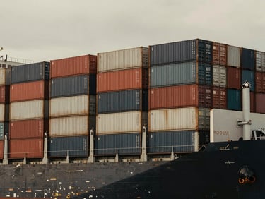 Wide geometric shot of massive cargo container vessel stacked with containers, overcast sky, muted charcoal and warm tones