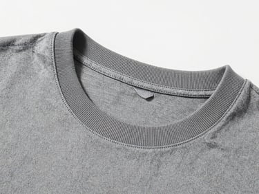 Stark studio product shot of a desaturated grey t-shirt collar, extreme close-up showing the thick ribbed texture and tight double-stitching, cold lighting.
