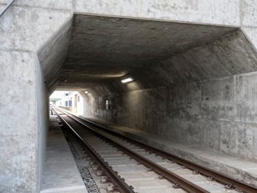 Crisp architectural shot of a subterranean metro rail tunnel with concrete reinforcement visible, cool industrial lighting