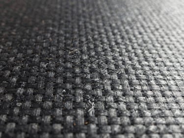 Extreme close-up of structural carbon fiber weave texture, crisp industrial studio lighting, sharp focus on composite fibers.