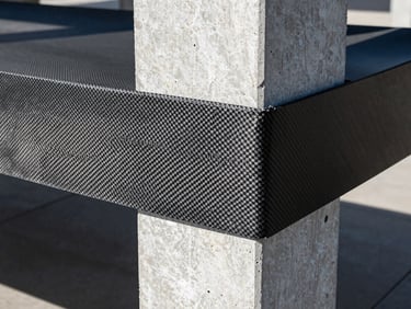 High-contrast close-up of carbon fiber fabric sheets being applied to a concrete column under high-intensity industrial lighting