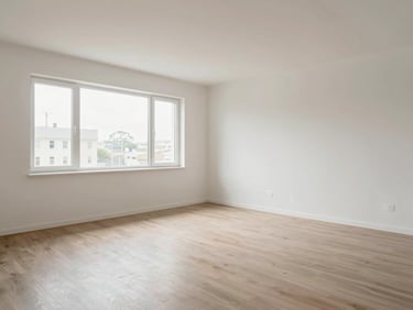 Wide environmental shot of the same living room completely cleared and cleaned, bare walls freshly wiped, clean floor without a trace of debris, natural daylight now filling the entire space through unobstructed windows, same framing angle as the before photo