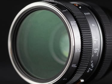 Close-up of a Freewell Variable ND filter, showing the rotating rings with clear markings, subtle green anti-reflective coating reflections, dramatic studio lighting, macro, 85mm.