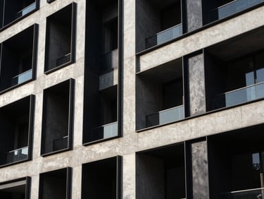 High-contrast commercial building facade of blackened steel and raw concrete, casting sharp geometric shadows under low-angle morning sun.