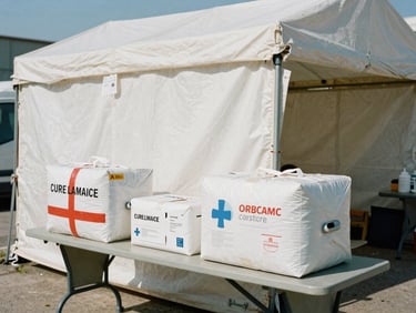 A temporary medical tent with emergency supplies on tables, natural harsh daylight