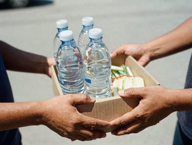 Close-up of hands handing over a box of fresh food and clean water, raw documentary style, high contrast