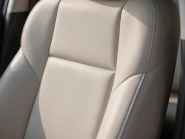 Macro crop of a pristine hand-stitched leather car seat cabin, soft north-facing daylight.