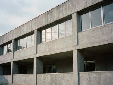 Quiet architectural detail of a modern concrete research facility facade, sharp overcast daylight, deep shadows, minimalist design, editorial film style.