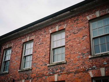Close-up of weathered red brickwork of a historic community building, soft diffused overcast daylight, high contrast, architectural texture.