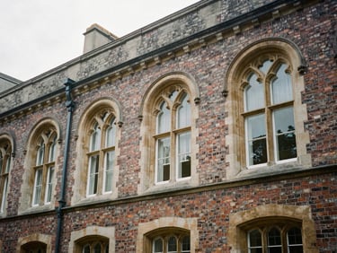 Quiet architectural detail of historical brickwork and arched windows of an old university library, soft overcast daylight, muted academic tones, 35mm lens.