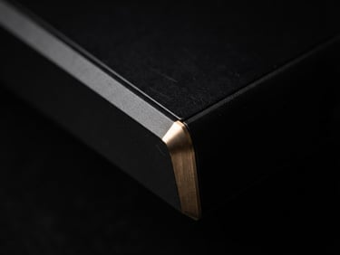 Extreme close-up of a sleek matte black device edge with a subtle gold glow, dramatic studio lighting, sharp details, macro lens