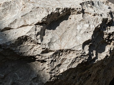 Extreme macro shot of raw travertine stone texture, showing deep cavities and natural veins in high-contrast light