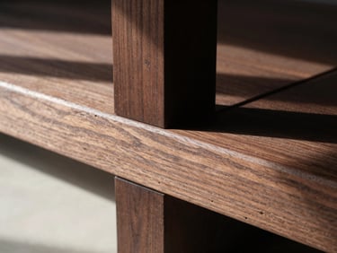 Close-up of a Japanese-style wood joint in dark walnut, showcasing the precise interlocking grain under sharp sunlight