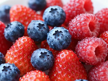 Macro shot of fresh glistening strawberries, blueberries, and raspberries piled high, water droplets, bright daylight, vibrant red and blue tones